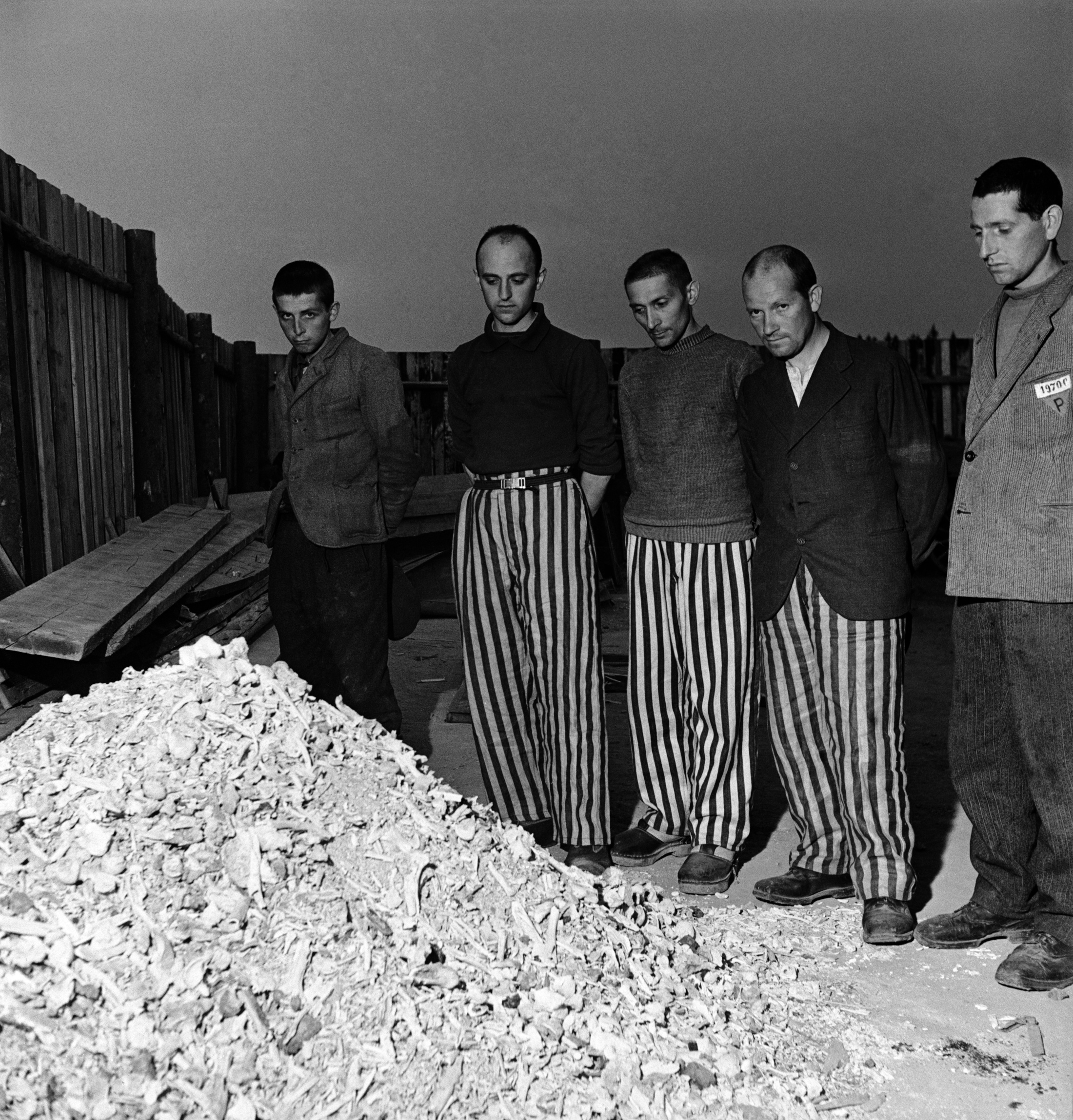 Lee Miller: Befreite Gefangene in gestreifter Gefängniskleidung neben einem Haufen aus Knochen von Leichen, die im Krematorium verbrannt wurden, Buchenwald, 1945